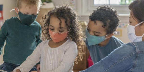 children and a teacher learning together while wearing protective masks