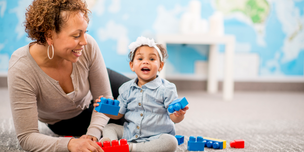 a teacher with a toddler playing with blocks