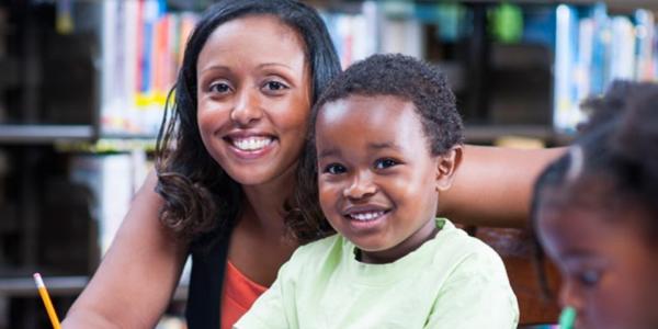 a happy teacher and child writing