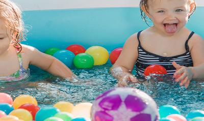 Toddlers playing with toy balls in pool