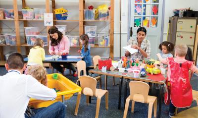 Two toddler teachers assisting play centers in classroom