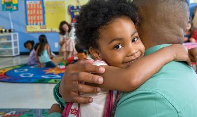 Girl hugging father in classroom