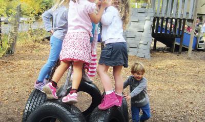 Four children playing on tire swing