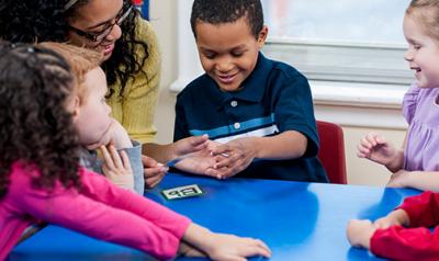 Teacher guiding preschool students at table