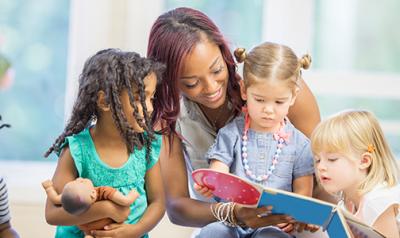 Teacher reads to preschoolers as they look through a book