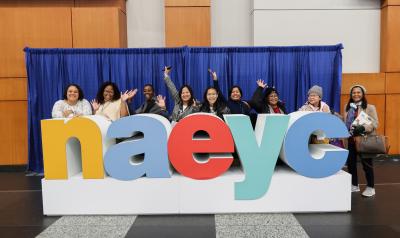 a group of people posing with a large statue of letters spelling n a e y c