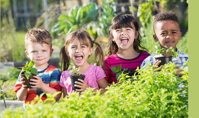 Group of diverse children holding plants outside