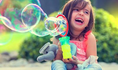 Preschool girl playing with bubbles outside