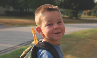 Child standing outside with backpack