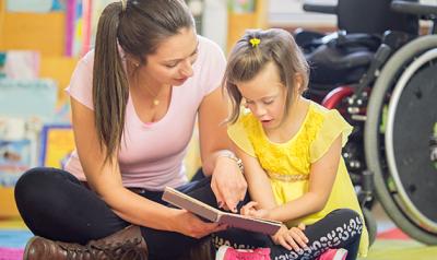 Teacher and student with a disability reading a book together