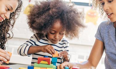 Two women and a young girl sitting at a table and playing with blocks