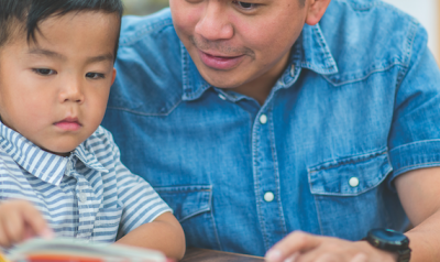 Male teacher and preschool student reading a book