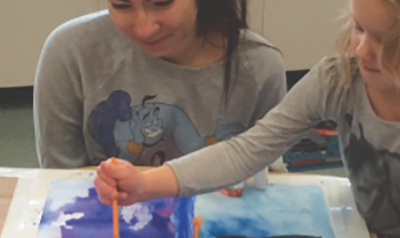 Teacher observes as child paints artwork