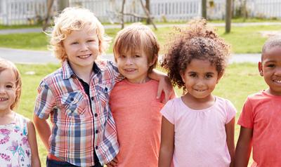 Preschool age children pose for a picture outdoors.