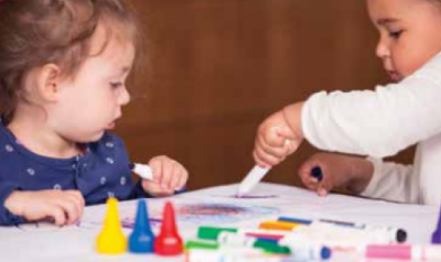 Two toddlers playing and drawing with assorted art materials