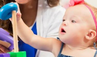 A toddler stacks colorful plastic rings