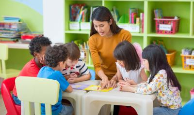 A teacher showing children a picture on a table