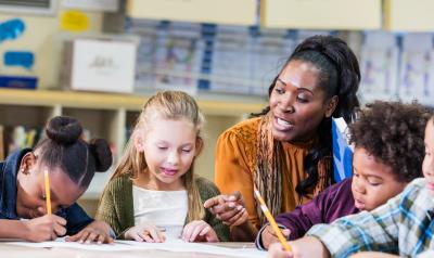 A teacher guides students as they write.