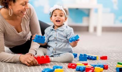 an adult playing with blocks with a toddler
