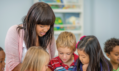 a teacher guiding children at a classroom table