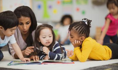 An early childhood educator reading a book to young children