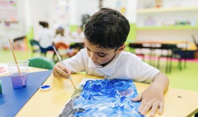 A young child painting in a classroom