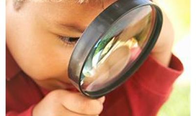 Boy with magnifying glass looking at the grass