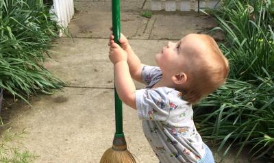 Toddler holding a broom outside