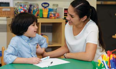 Teacher helping student write with markers