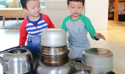 Two boys playing with pots on the kitchen floor