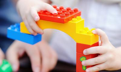 Parent and child's hands building with legos
