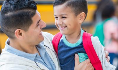 Father and son hugging by the school bus