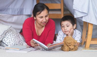 Mother and son reading a book on the floor of a child's room