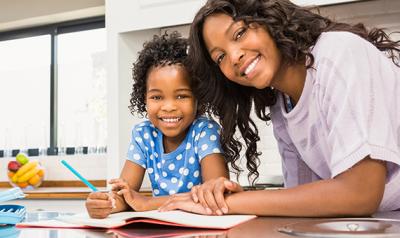 Mother and daughter at the kitchen table doing homework