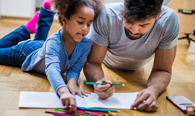 Father and daughter talking and coloring on the floor