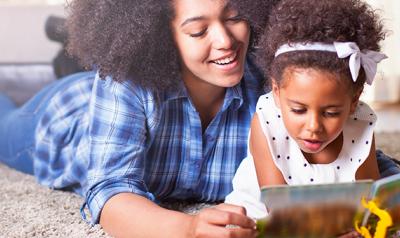 Toddler reading book with mother