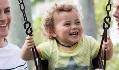 Moms helping toddler on swing