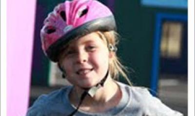 Young girl on a bike wearing a pink helmet