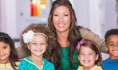 Teacher and preschoolers smiling in a classroom