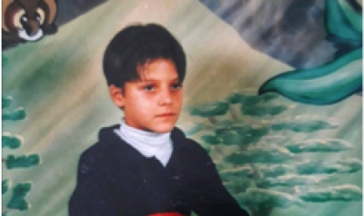 A picture of the author in 3rd grade.  Shows a boy sitting in front of a painted background.