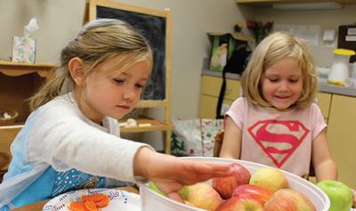 Two young girls with bucket of apples