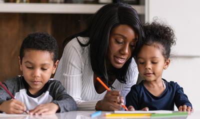 A teacher writing with children at a table.