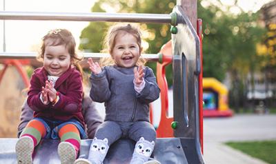 two laughing children sitting on a slide