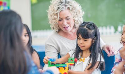 A teacher watching her students play with manipulatives.