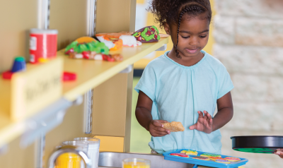 a young child playing with a pretend kitchen toyset