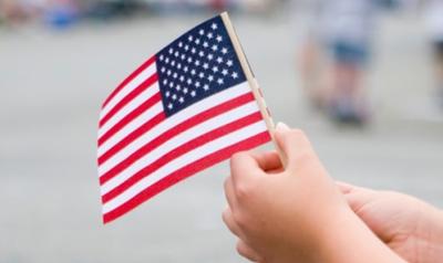 a childs hands holding a small american flag