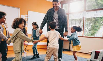 Teacher dancing in a circle with students in classroom