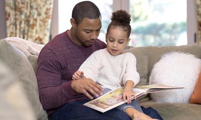 Young girl reading a book with her father