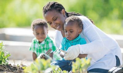 Teacher helping two students with gardening