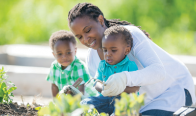 Mom helping toddler sons plant garden